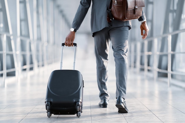 Uomo d'affari viaggio d'affari che porta la valigia vista posteriore
