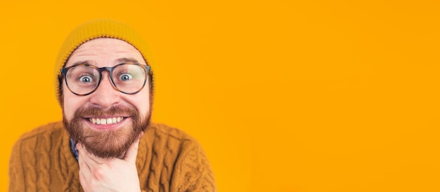 Uomo dalla barba rossa che guarda la telecamera su uno sfondo arancione che fa una faccia sciocca