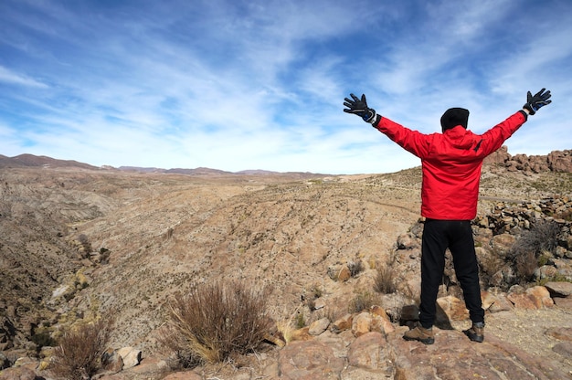 Uomo dalla parte posteriore in piedi con le braccia aperte nel paesaggio in Bolivia