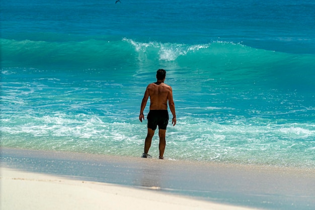 Uomo davanti all'onda del mare