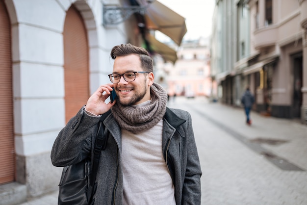 Uomo dei pantaloni a vita bassa che parla sullo Smart Phone nella città di inverno.