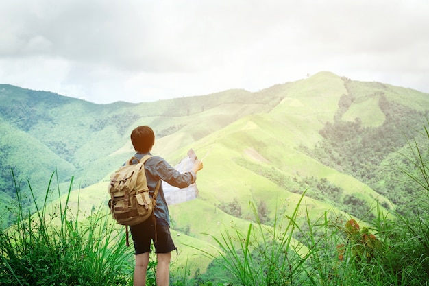 uomo dei pantaloni a vita bassa che tiene mappa delle montagne con splendida vista