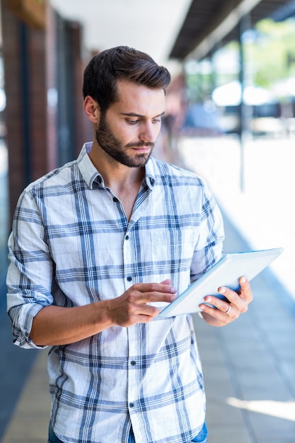 Uomo dei pantaloni a vita bassa che utilizza il computer della compressa nella città