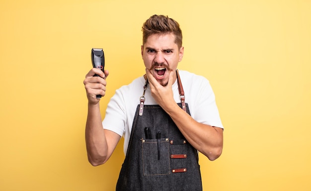 Uomo del barbiere hipster con la bocca e gli occhi spalancati e la mano sul mento