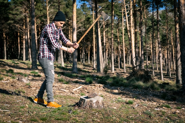 Uomo del boscaiolo che taglia la legna con l'ascia nella foresta