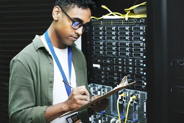 Uomo del centro dati e ingegnere informatico con scrittura di liste di controllo e note come programmatore Persona maschile ispezione e tecnologia per la sicurezza dell'hardware e sala server per l'aggiornamento o la manutenzione del sistema