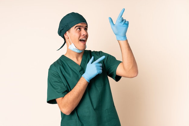 Uomo del chirurgo in uniforme blu sopra la parete che indica con il dito indice una grande idea