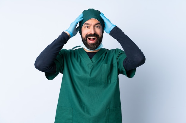 Uomo del chirurgo in uniforme verde sopra la parete con l'espressione sorpresa