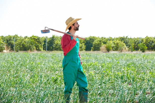 Uomo del coltivatore con zappa guardando il suo campo