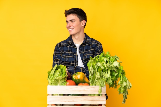 Uomo del coltivatore dell'adolescente con le verdure di recente selezionate in una risata della scatola