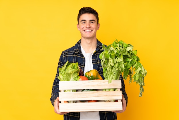 Uomo del coltivatore dell'adolescente con le verdure di recente selezionate in una scatola