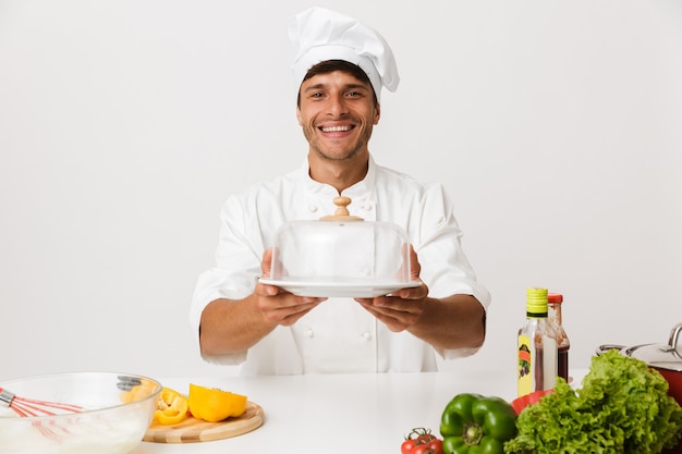 Uomo del cuoco unico isolato sulla cucina bianca della parete.