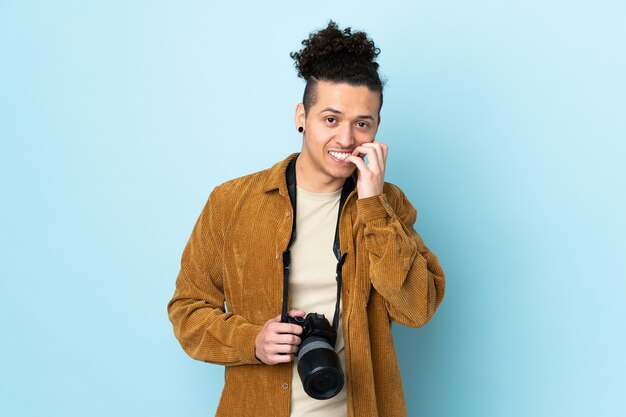 Uomo del fotografo sopra fondo blu isolato nervoso e spaventato