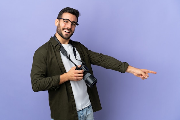Uomo del fotografo sopra la parete viola isolata che indica barretta il lato e che presenta un prodotto