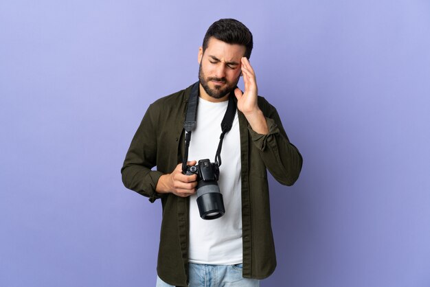 Uomo del fotografo sopra la parete viola isolata con l'emicrania