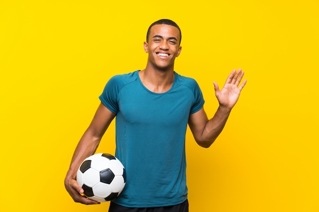 Uomo del giocatore di football americano africano che saluta con la mano con l'espressione felice