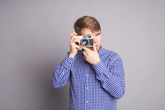 Uomo del giovane fotografo che tiene retro macchina fotografica su gray