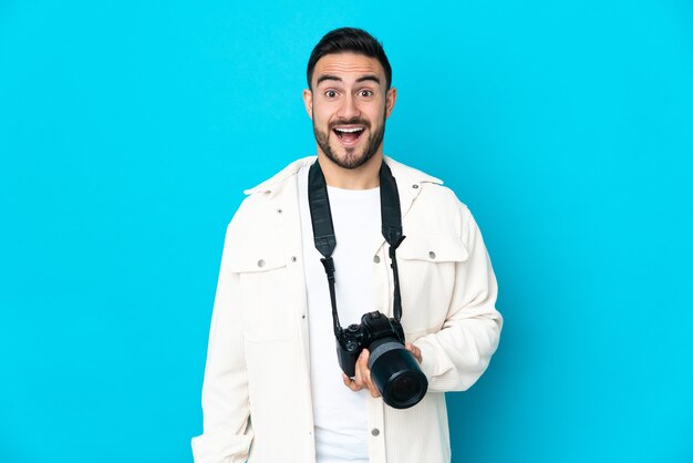 Uomo del giovane fotografo isolato sulla parete blu con l'espressione facciale di sorpresa