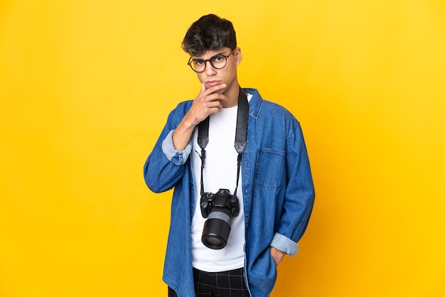 Uomo del giovane fotografo sopra il pensiero giallo isolato della priorità bassa