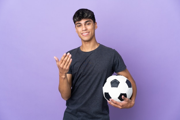 Uomo del giovane giocatore di football americano sulla porpora isolata che invita a venire con la mano. Felice che tu sia venuto