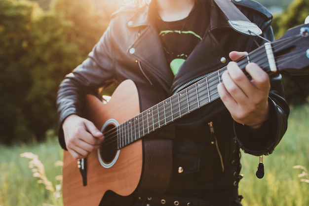 Uomo del musicista che suona la chitarra al primo piano del tramonto