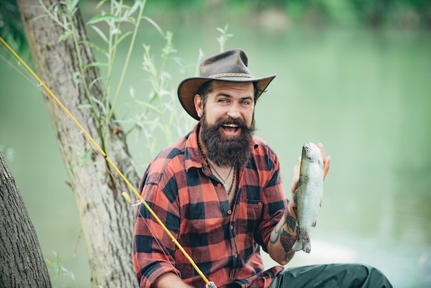 Uomo del pescatore sul fiume o sul lago con la canna da pesca Vacanze primaverili