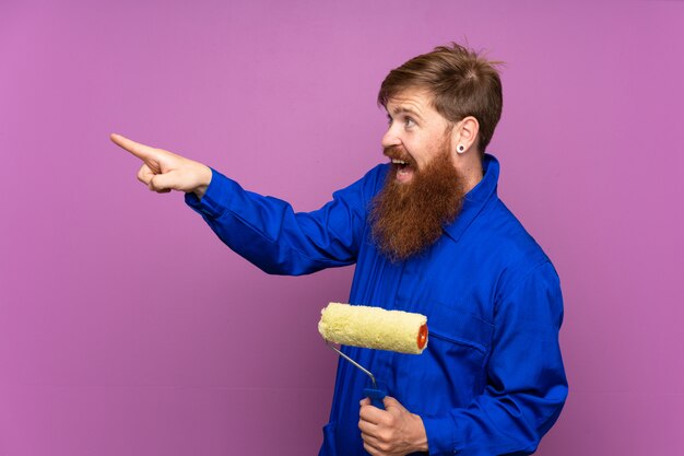 Uomo del pittore con la barba lunga sopra il dito indicante viola isolato al lato