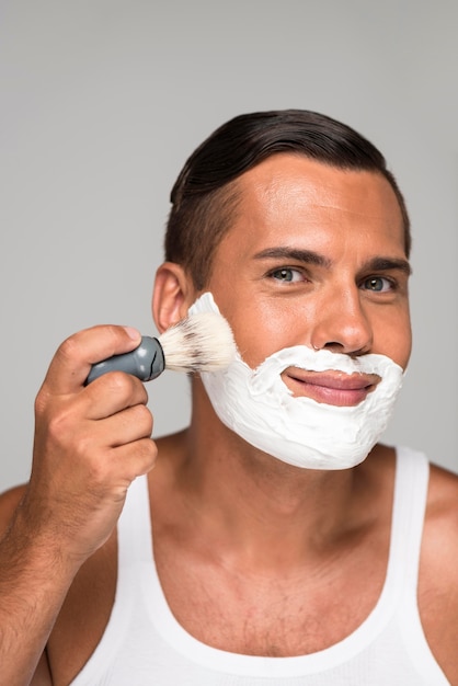 Uomo del primo piano che usando la crema da barba