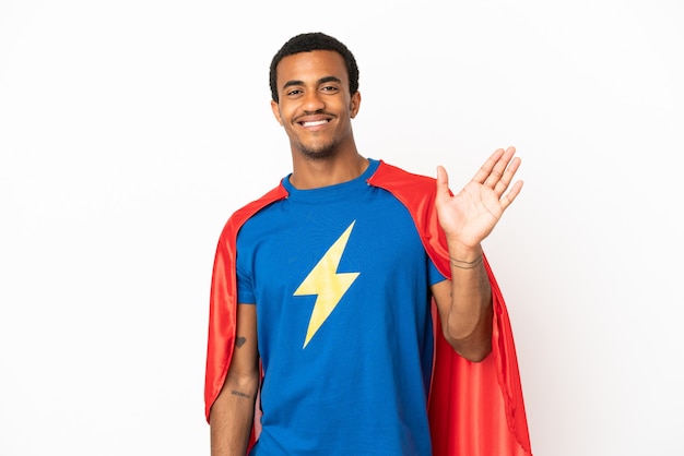 Uomo del super eroe afroamericano sopra fondo bianco isolato che saluta con la mano con l'espressione felice