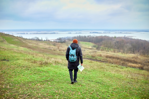 Uomo del viaggiatore con lo zaino con la mappa in mano su una parete del fiume delle montagne della natura, concetto di viaggio, vacanze e concetto di escursionismo di stile di vita