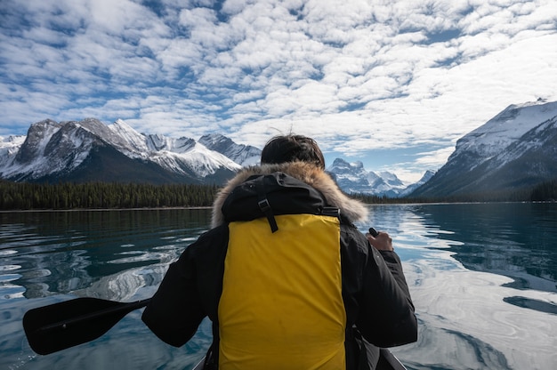 Uomo del viaggiatore in canoa con le Montagne Rocciose Canadesi sul lago Maligne al parco nazionale di Jasper, AB, Canada