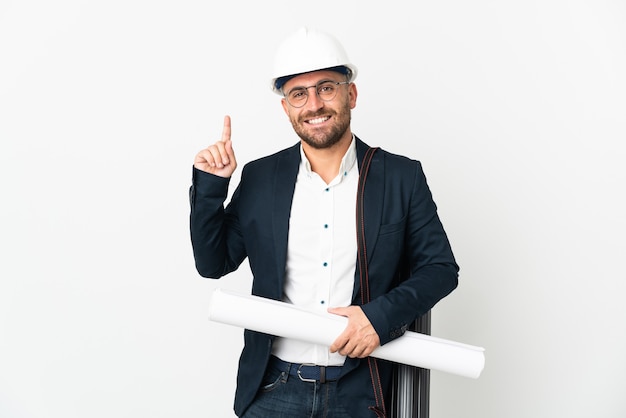 Uomo dell'architetto con il casco e che tiene i modelli isolati su bianco che indica su una grande idea