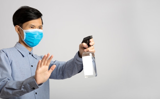 Uomo dell'Asia che utilizza la pulizia dell'alcool dello spruzzo per proteggere i batteri anti virus. Misure preventive contro il virus corona.