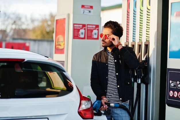 Uomo dell'Asia meridionale o maschio indiano che rifornisce di carburante la sua auto bianca sulla stazione di servizio.