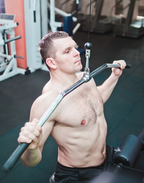 Uomo dell'atleta in palestra che fa spinta verticale.