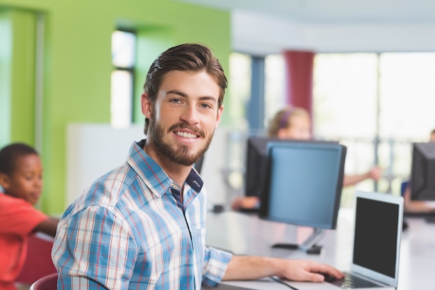 Uomo dell'insegnante che utilizza computer portatile nell'aula