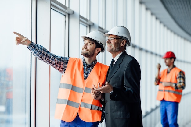 Uomo dell'operaio edile che punta su piani architettonici e architetto