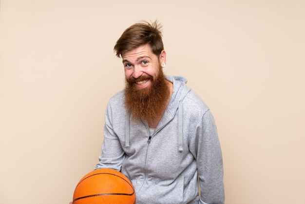 Uomo della testarossa con la barba lunga sopra fondo isolato con la palla di pallacanestro
