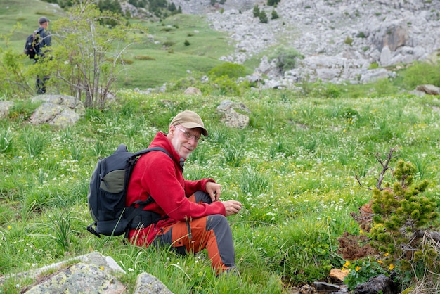 Uomo della viandante con lo zaino che si rilassa nel paesaggio della montagna