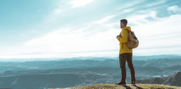 Uomo della viandante sulla cima della montagna che osserva la vista del paesaggio