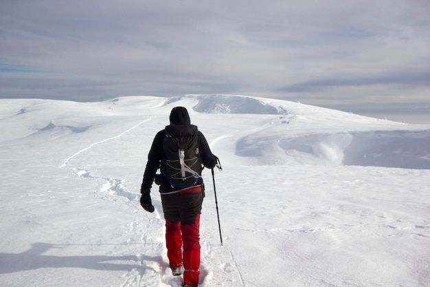 Uomo dello scalatore che cammina nella neve