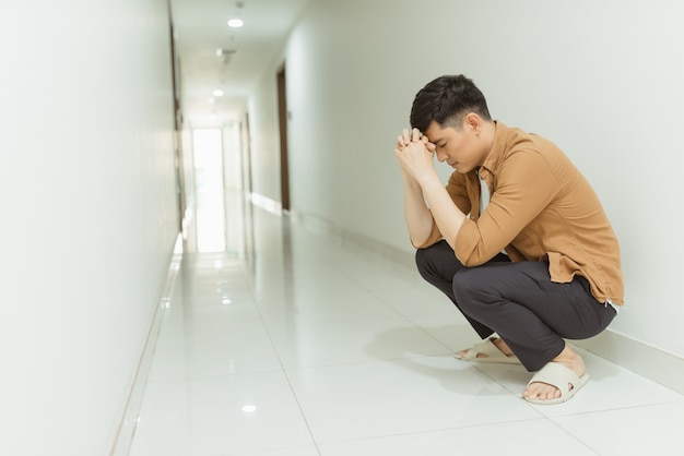 Uomo depresso che ha perso la fede seduto da solo in un corridoio