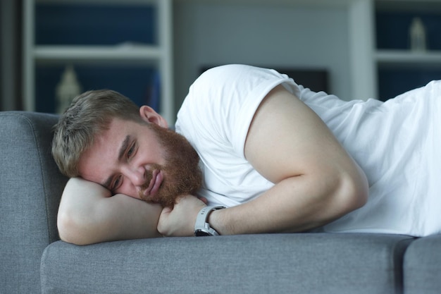 Uomo depresso deluso con il cuore spezzato a causa della rottura piangendo abbondantemente sdraiato sul divano