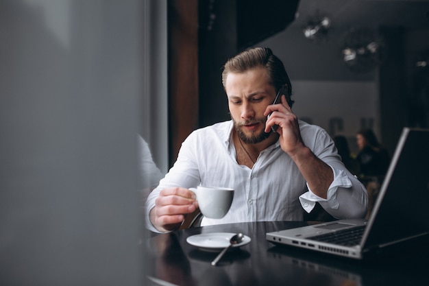 Uomo di affari che lavora con il computer portatile e che beve caffè in un caffè