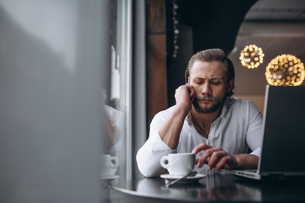 Uomo di affari che lavora con il computer portatile e che beve caffè in un caffè