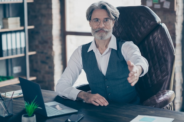 Uomo di affari che solleva la mano per la stretta di mano in ufficio workstation