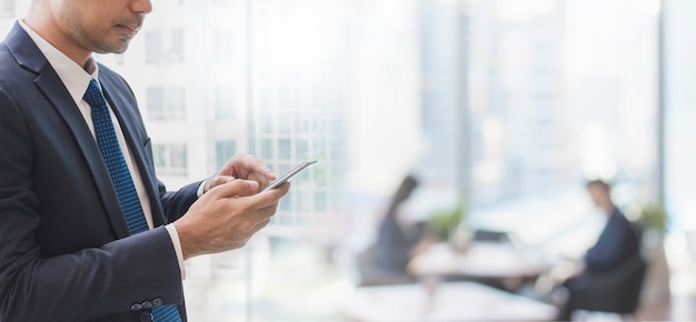 Uomo di affari che utilizza Smart Phone nel fondo dell&#39;insegna dello spazio ufficio e spazio della copia.