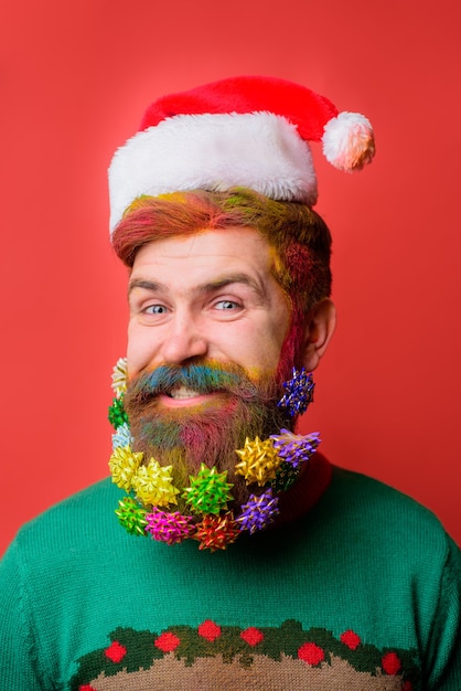 Uomo di babbo natale con barba decorata uomo barbuto sorridente in cappello di babbo natale decorazioni per la barba