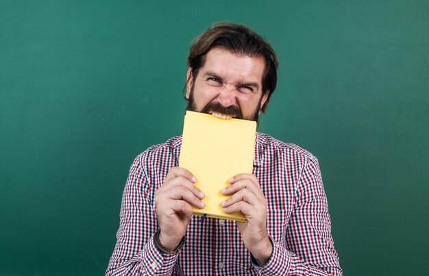 Uomo di college maturo arrabbiato che morde lo stress del libro