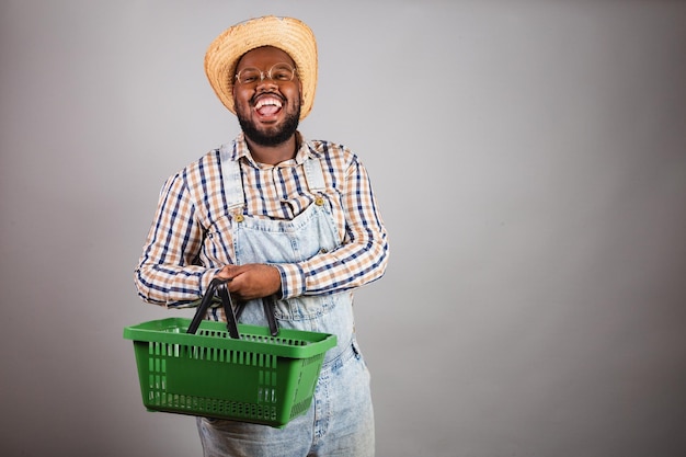 Uomo di colore brasiliano che indossa abiti da campagna della festa junina festa de sao joao arraia che tiene promozioni per lo shopping nel paniere del mercato